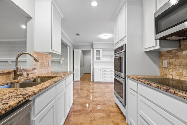 kitchen with backsplash, white cabinets, sink, light stone countertops, and stainless steel appliances