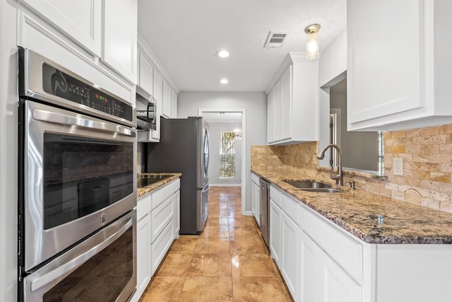 kitchen featuring dark stone countertops, white cabinetry, sink, and appliances with stainless steel finishes