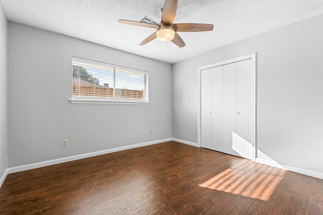 unfurnished bedroom with a textured ceiling, a closet, ceiling fan, and dark wood-type flooring