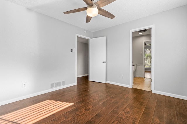 unfurnished bedroom featuring a textured ceiling, dark hardwood / wood-style flooring, ceiling fan, and connected bathroom