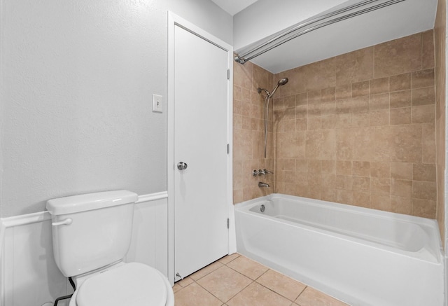 bathroom with tile patterned floors, tiled shower / bath, and toilet