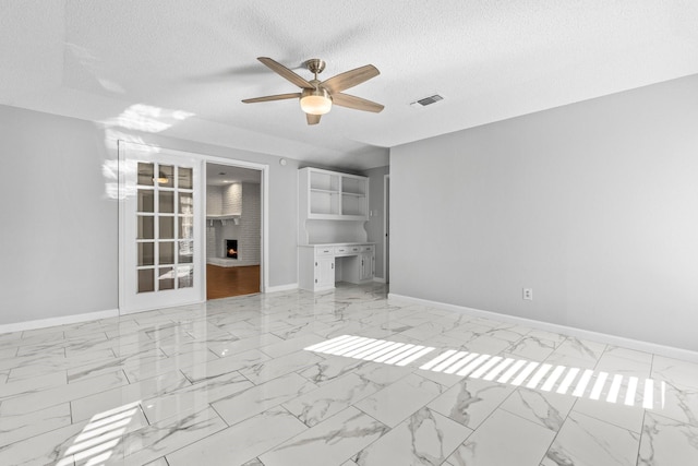 unfurnished living room with ceiling fan, a fireplace, and a textured ceiling