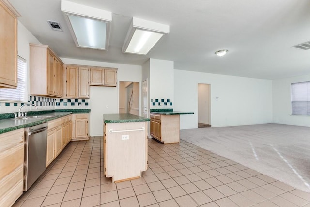 kitchen featuring dishwasher, light brown cabinets, sink, light colored carpet, and a kitchen island