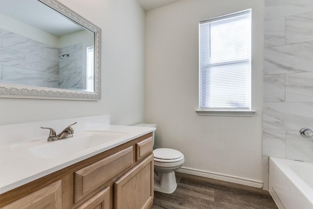 full bathroom featuring hardwood / wood-style floors, vanity, toilet, and tiled shower / bath