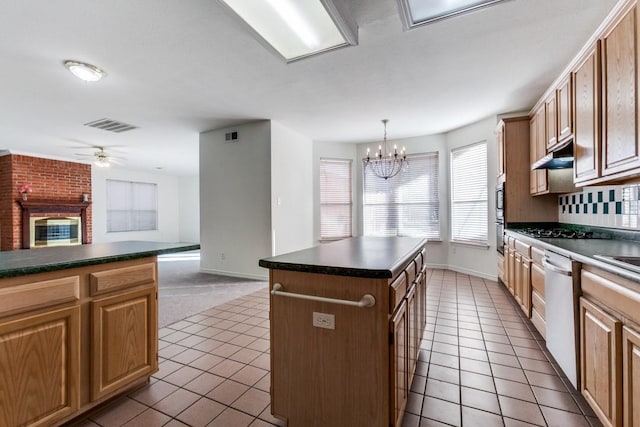 kitchen featuring a brick fireplace, tile patterned floors, ceiling fan with notable chandelier, pendant lighting, and a kitchen island