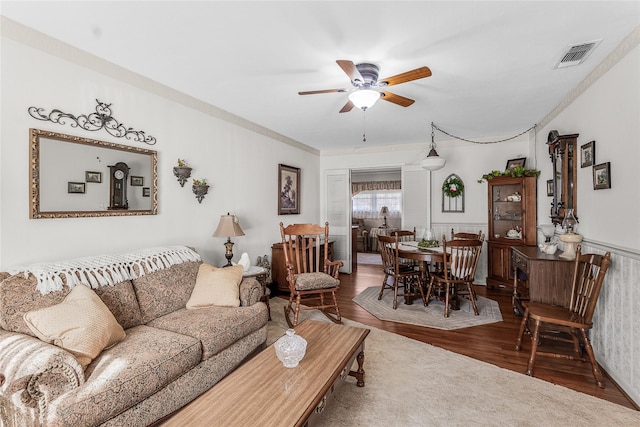 living room featuring ceiling fan, wood-type flooring, and crown molding