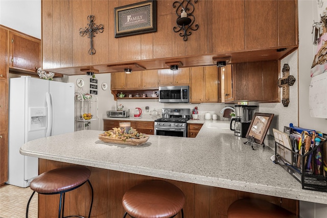 kitchen featuring a kitchen bar, kitchen peninsula, sink, and stainless steel appliances