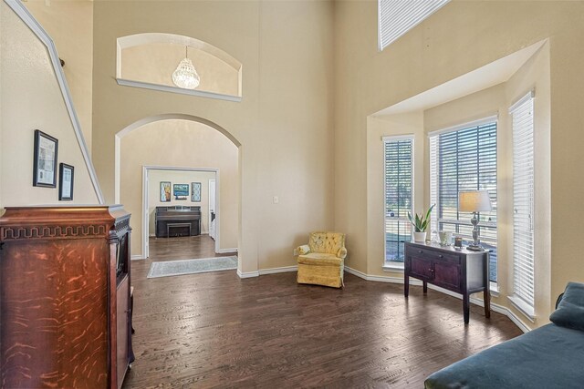 living area featuring a towering ceiling, dark wood-type flooring, and an inviting chandelier