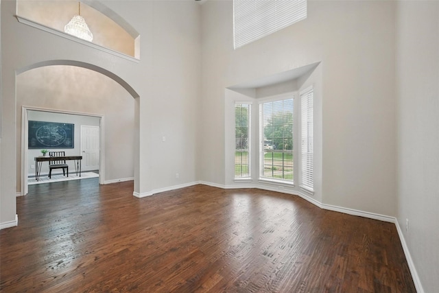 122 Wentwood Dr, Murphy, TX 75094 - unfurnished room featuring arched walkways, wood finished floors, and a towering ceiling