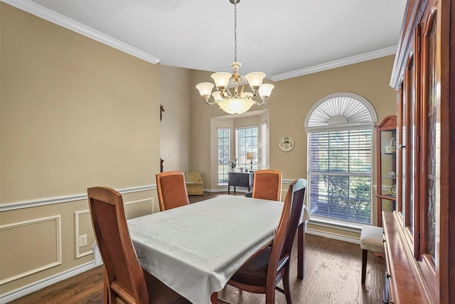 dining area with dark hardwood / wood-style flooring, ornamental molding, and an inviting chandelier