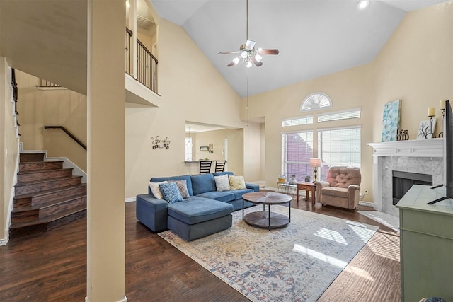 living room with a premium fireplace, dark hardwood / wood-style flooring, ceiling fan, and high vaulted ceiling