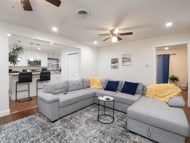 living room featuring ceiling fan and dark wood-type flooring