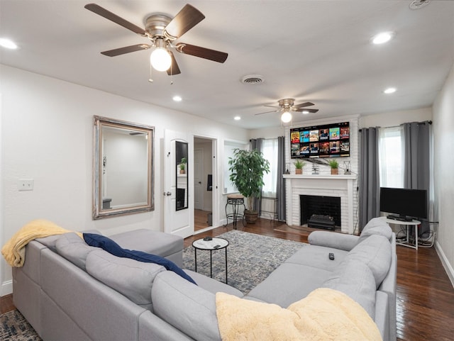 living room with ceiling fan, dark hardwood / wood-style flooring, and a brick fireplace