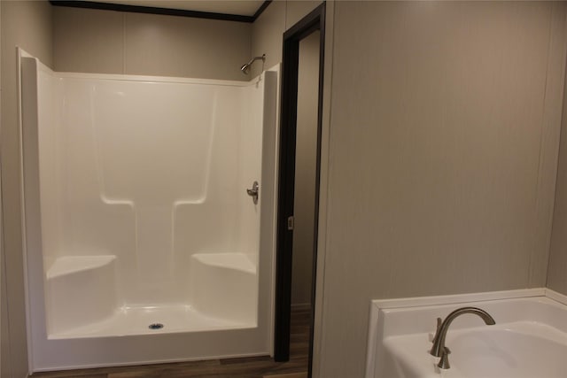 bathroom featuring plus walk in shower and hardwood / wood-style flooring