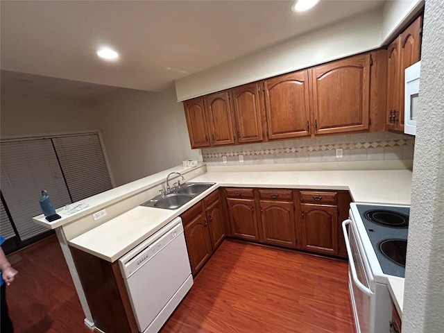 kitchen featuring dark hardwood / wood-style floors, sink, white appliances, and kitchen peninsula