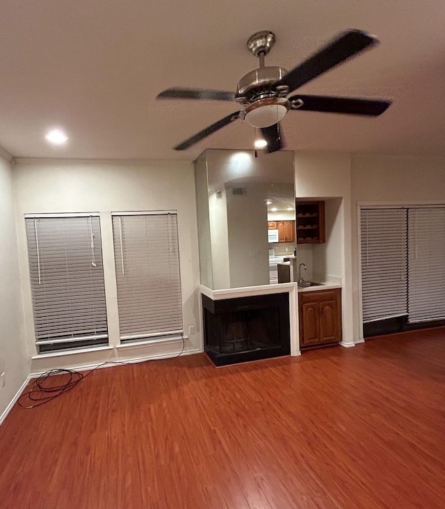 unfurnished living room with ceiling fan, sink, and hardwood / wood-style flooring