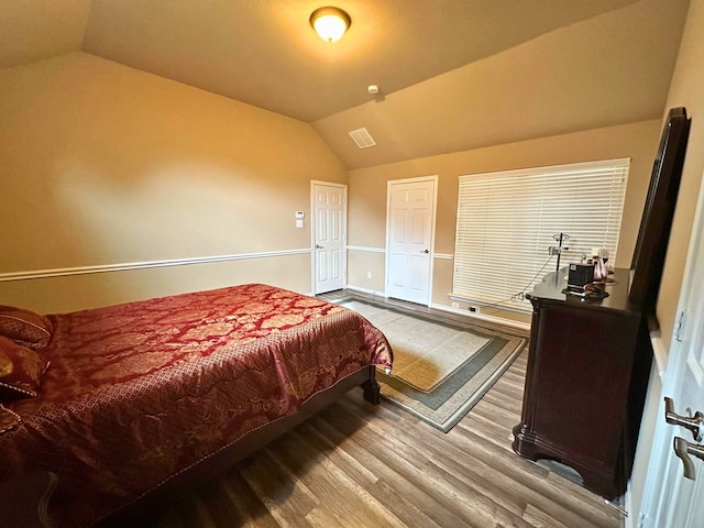 bedroom with hardwood / wood-style floors and lofted ceiling