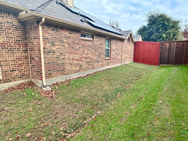 view of property exterior with a lawn and solar panels