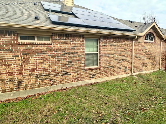 view of side of home featuring solar panels and a lawn