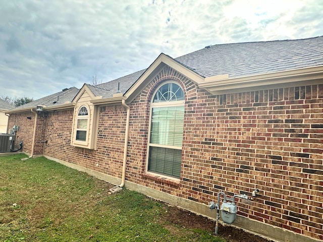 view of side of home with cooling unit and a yard