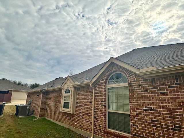 view of side of property with central AC and a lawn