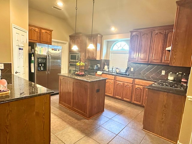 kitchen featuring decorative backsplash, appliances with stainless steel finishes, sink, decorative light fixtures, and a center island