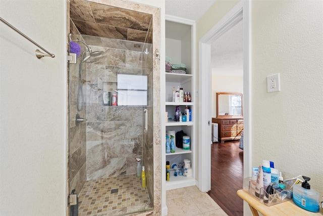 bathroom with a textured ceiling, hardwood / wood-style flooring, and a shower with door