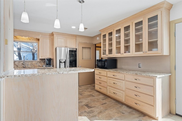 kitchen with light stone countertops, a center island, sink, stainless steel fridge, and pendant lighting