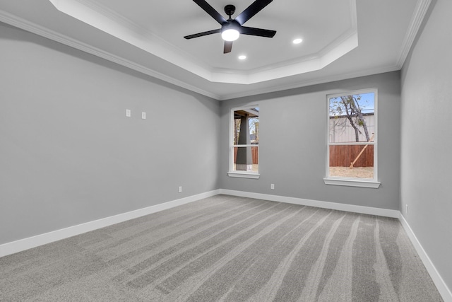 empty room with carpet floors, a raised ceiling, ceiling fan, and crown molding