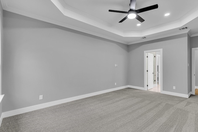 spare room with a raised ceiling, light carpet, ceiling fan, and ornamental molding