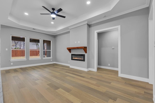 unfurnished living room featuring a tray ceiling and light hardwood / wood-style floors