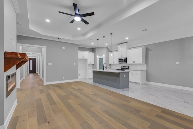 kitchen with pendant lighting, white cabinets, a center island with sink, sink, and appliances with stainless steel finishes