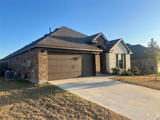 view of front facade featuring cooling unit, a garage, and a front lawn