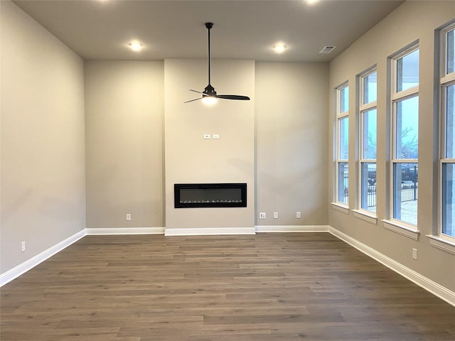 unfurnished living room with dark hardwood / wood-style floors, a wealth of natural light, and ceiling fan