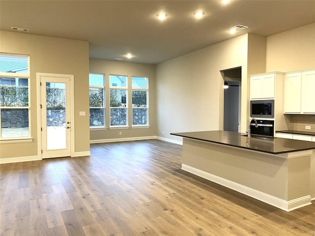 kitchen with built in microwave, sink, white cabinetry, wood-type flooring, and wall oven