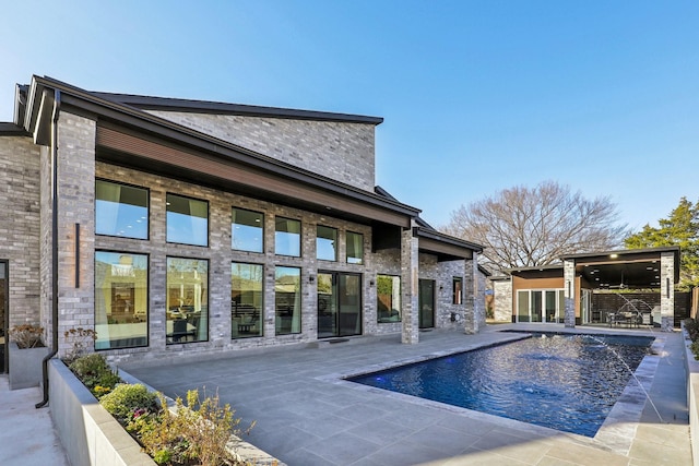 view of swimming pool with pool water feature and a patio