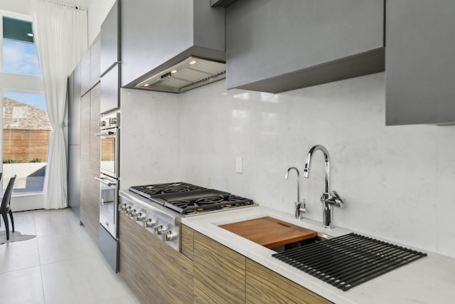 kitchen featuring stainless steel gas cooktop, a wealth of natural light, premium range hood, and light tile patterned flooring