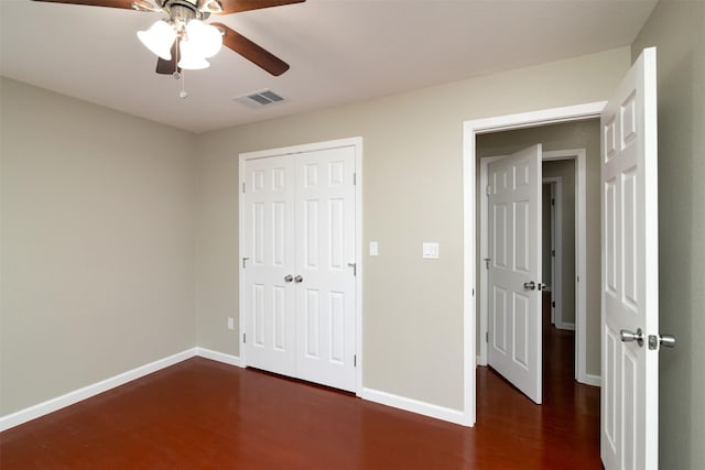 unfurnished bedroom with a closet, dark hardwood / wood-style floors, and ceiling fan