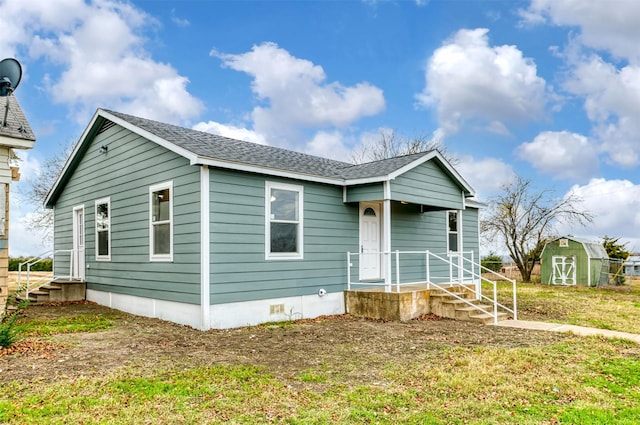 view of front of house featuring a front lawn and a shed