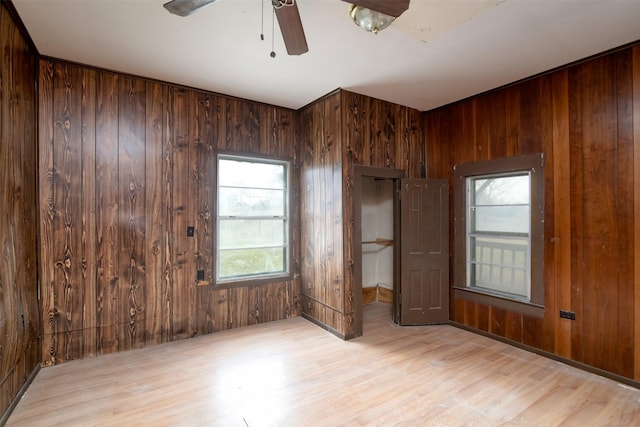 unfurnished bedroom with wood walls, light hardwood / wood-style flooring, and ceiling fan