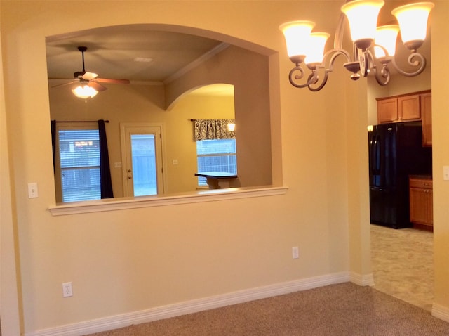 carpeted spare room featuring ceiling fan with notable chandelier and crown molding