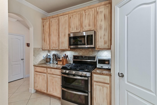 kitchen featuring light brown cabinets, backsplash, dark stone countertops, light tile patterned floors, and appliances with stainless steel finishes