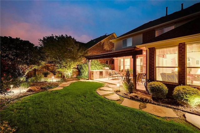 yard at dusk with a patio and area for grilling