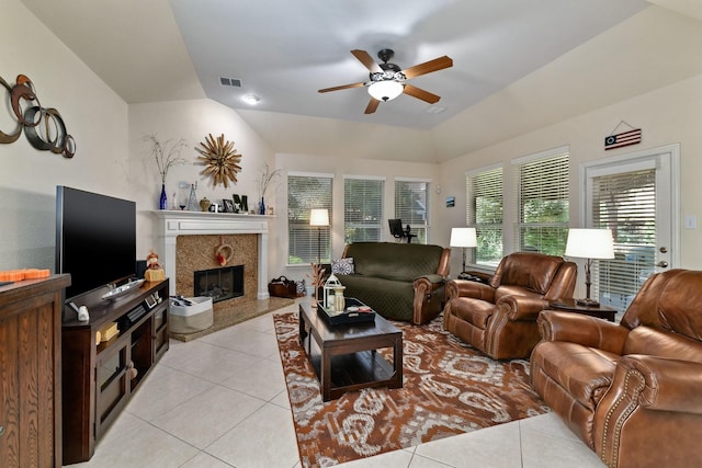 living room featuring a tiled fireplace, ceiling fan, light tile patterned floors, and vaulted ceiling