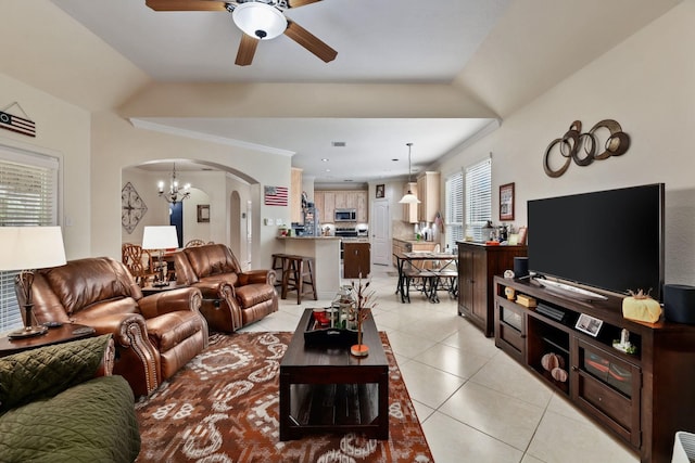 living room featuring ceiling fan with notable chandelier, light tile patterned floors, ornamental molding, and vaulted ceiling