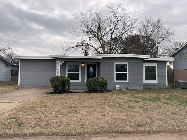 ranch-style house featuring cooling unit and a front lawn