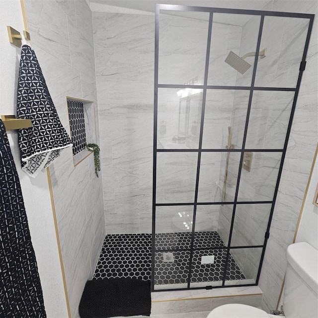 bathroom with a tile shower and toilet