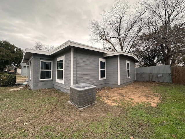 rear view of house featuring a lawn and central air condition unit