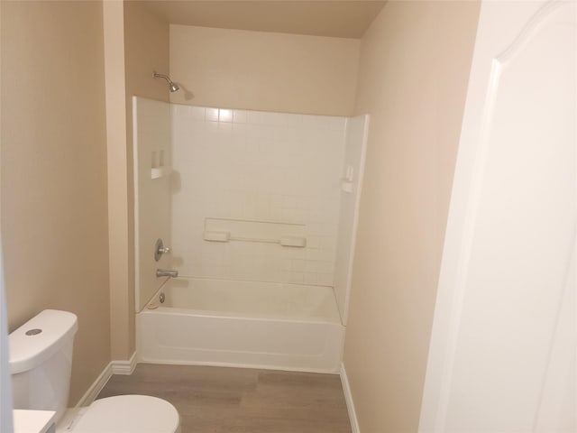 bathroom with washtub / shower combination, hardwood / wood-style flooring, and toilet