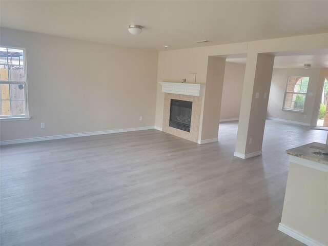 unfurnished living room with a fireplace, plenty of natural light, and light wood-type flooring